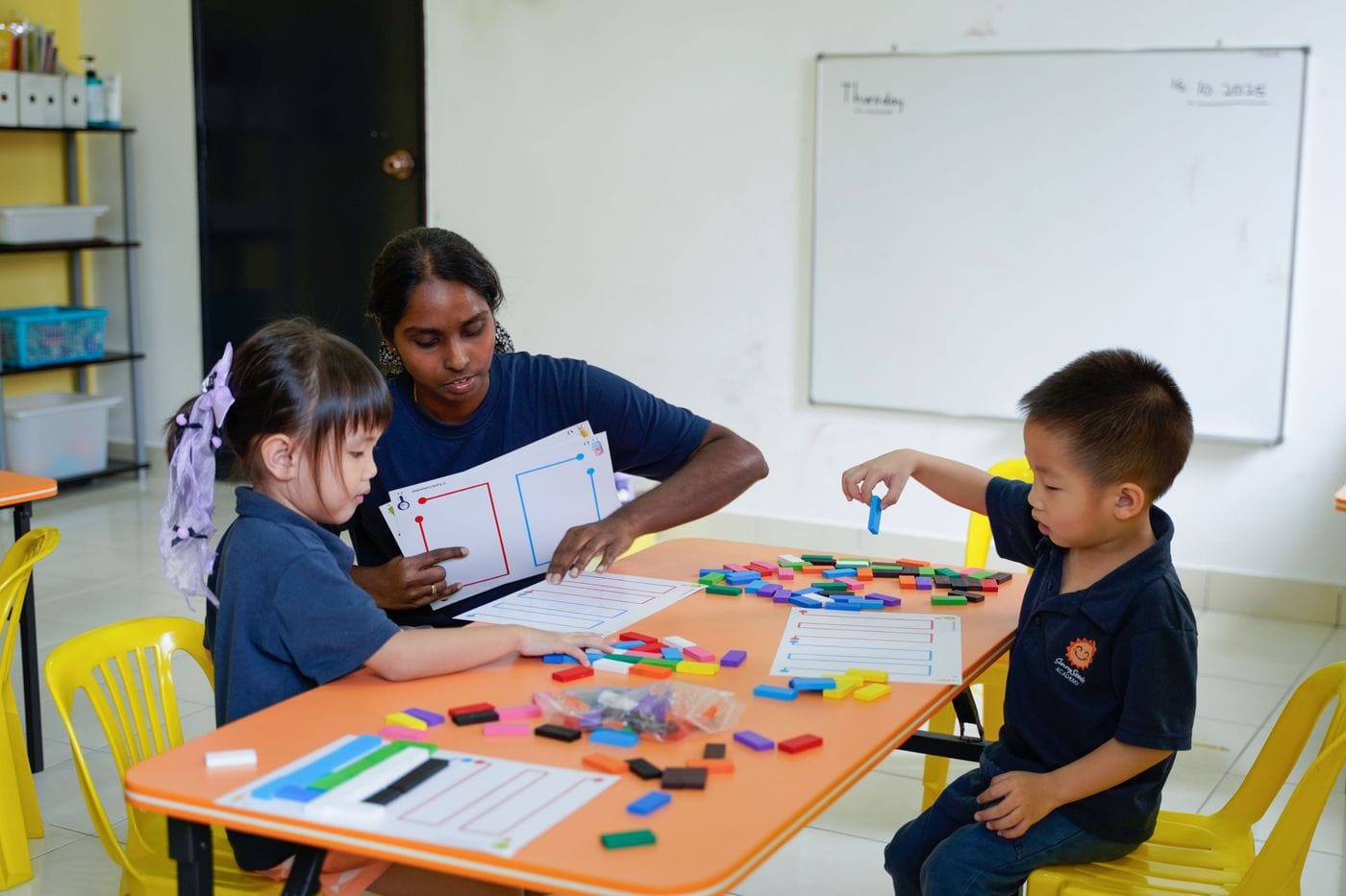 A SunnySeeds teacher working through a pattern activity with two children