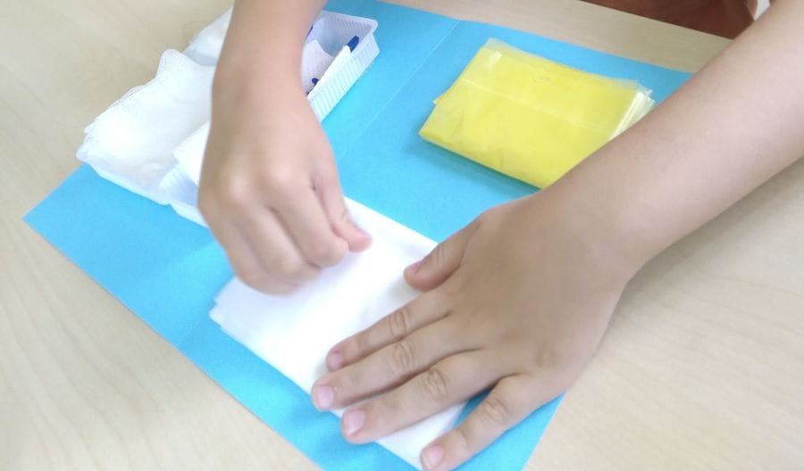 Small hands folding a cloth during a practical life activity