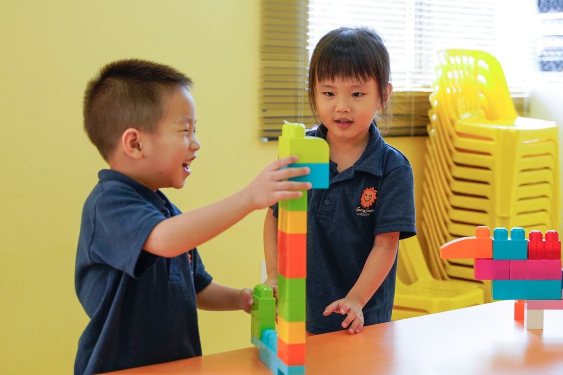 Two nursery children building a tower of blocks